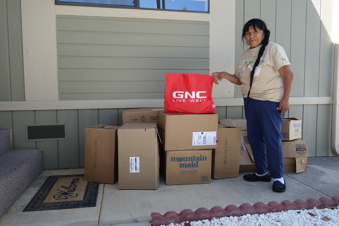 Tribal Elder and Food For Tribal Families, ( FFTF ) Director Mildred Burley stands with this months donations.