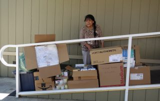 California Valley Miwok Tribe elder Mildred Burley standing in front of good supplies during June 2021 Food For Tribal Families Distribution