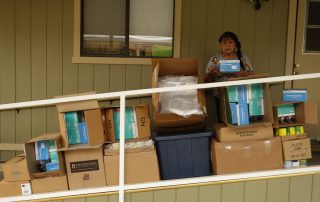 Mildred Burley, California Valley Miwok Tribe's elder, standing with good supplies from July 2021 food distribution.