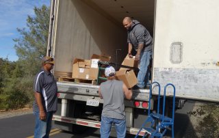 Tule River Food Distribution Specialists helping California Valley Miwok Tribal staff Tiger Paulk to unload good supplies.