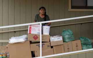 California Valley Miwok Tribal elder Mildred Burley standing with good supplies.