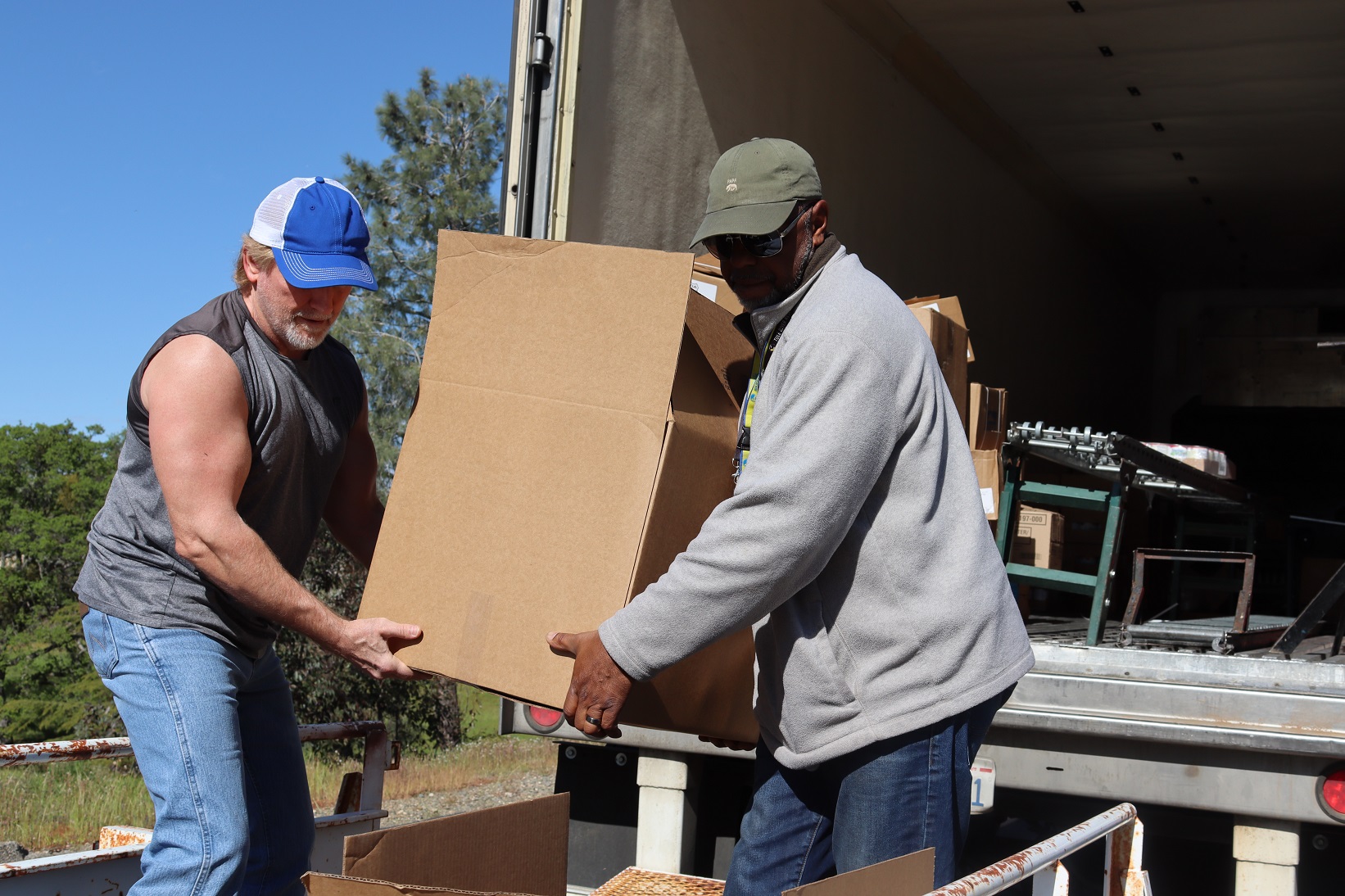 Ronald Buckman and Tiger Paulk unloading big boxes during a food distribution for the California Valley Miwok Tribe.