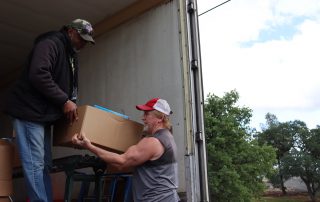 Ronald Buckman handing tribal staff member Tiger Paulk goods for the California Valley Miwok Tribe.