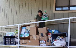 California Valley Miwok Tribe's elder Mildred Burley holding a loaf of bread in front of boxes of goods.