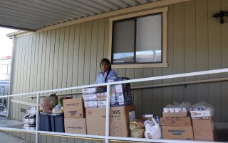 California Indian tribe elder Mildred Burley standing in front of food supplies for the California Valley Miwok Tribe.