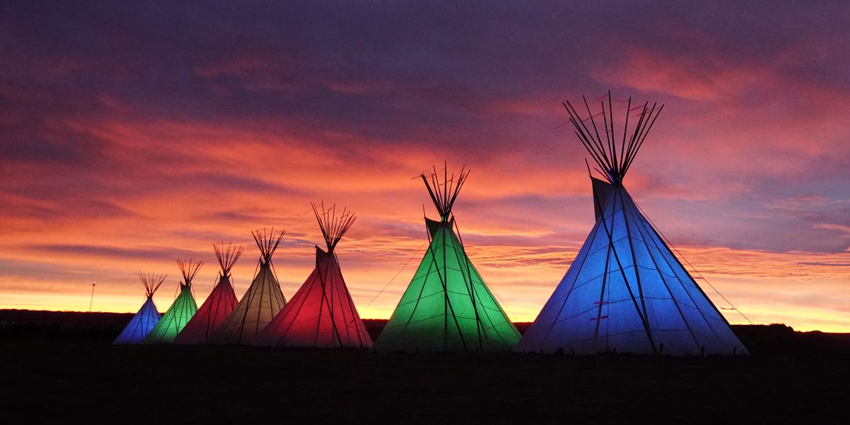 Colorful Native American tipis with a sunset.