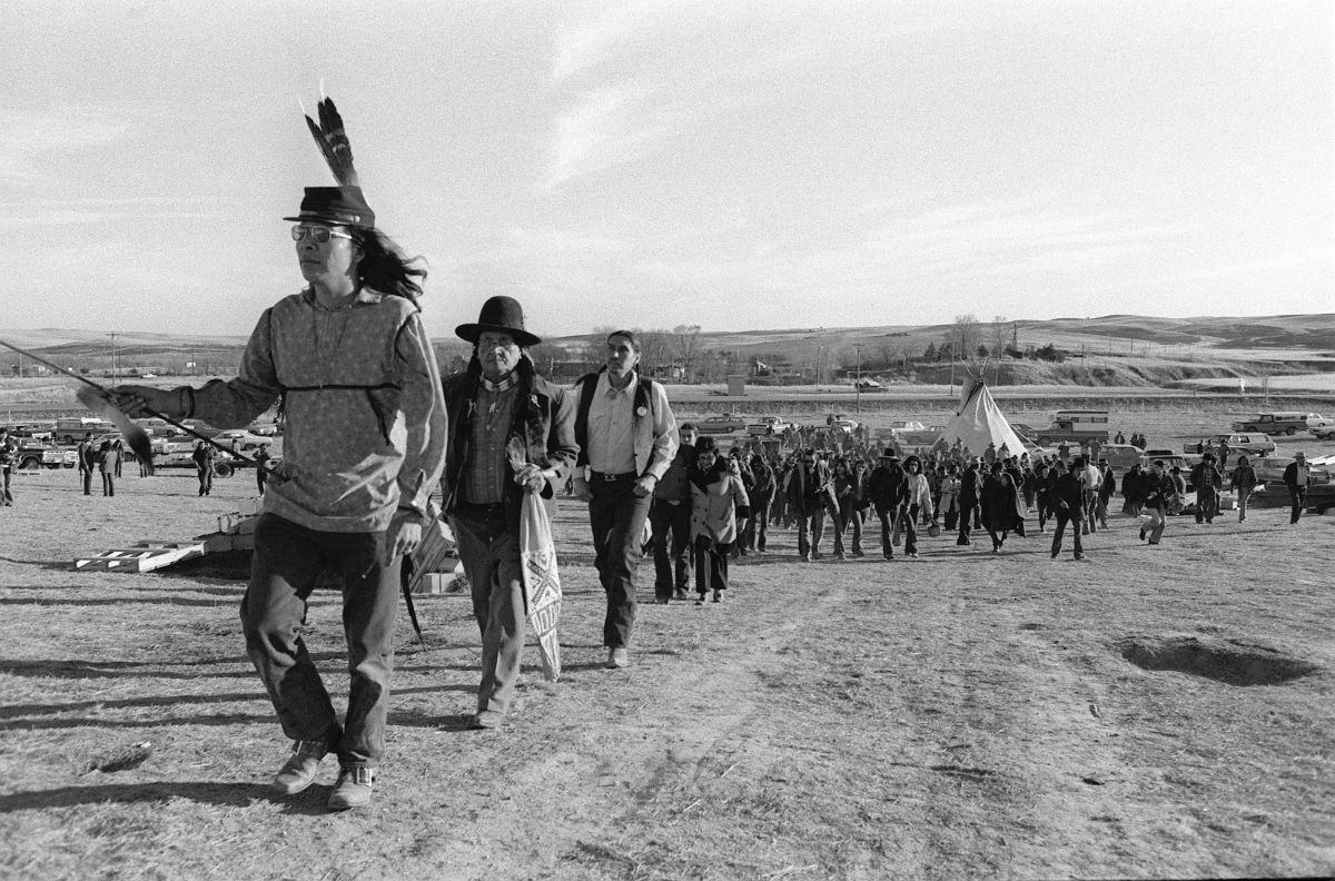 Oglala Sioux tribal members and AIM members march to to the cemetery where ancestors were buried following the 1890 massacre at the site.