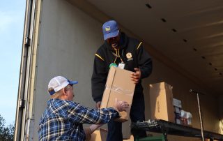 Ronald Buckman helping Tiger Paulk to unload goods for the Miwok tribe.