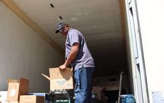 Ronald Buckman helping CMVT's staff member unloading the boxes of goods.