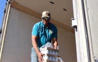 Ronald Buckman helps Tiger Paulk unloading goods during a food distribution in October 2024.