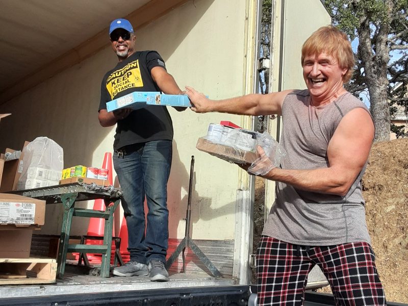 Although in a jovial mood safety is no laughing matter as in this case where Specialist Ronald Buckman and tribal staff leaned back while extending arms in the transference of food. June 2020 USDA Food Distribution