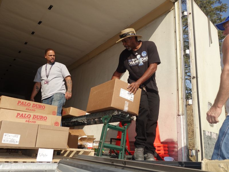 Naz keeping conveyor loaded while Ronald buckman lets him know what foods are needed next.
