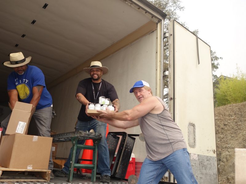 Specialist Ronald Buckman opening additional product as Specialist Naz hands product to tribal staff, all the while as all three try to keep social distancing.