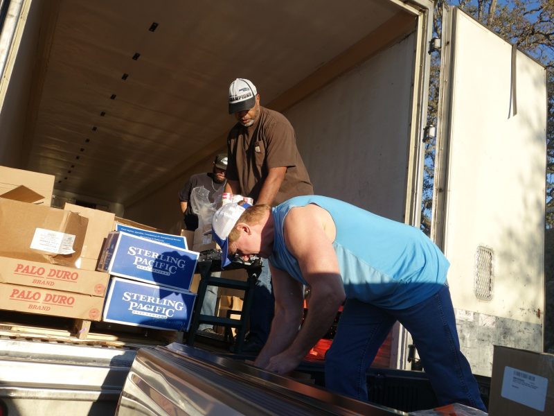 Already well into the distribution tribal personnel is loading delivery truck for those who could not attend as Tule River Food Specialist Ronald Buckman waits with commodities in hand and specialist Naz in background continues to load conveyor.