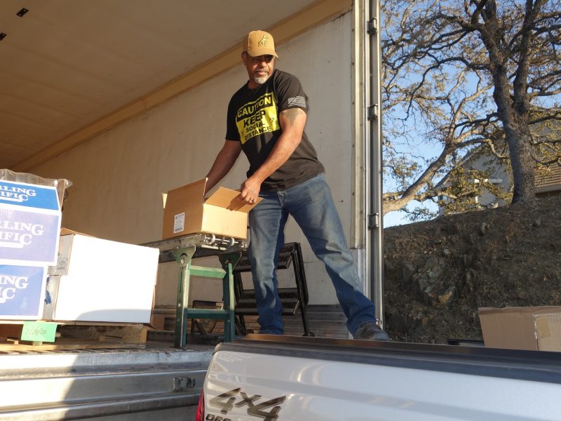 Tule River Food Distribution Specialist Ronald Buckman, seen here (wearing his, "Caution Keep Social Distance" shirt) during the loading of the tribal delivery vehicle.