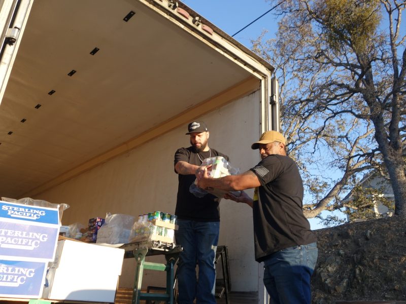 With conveyor fully loaded with last distribution's of the day, specialist Naz hands specialist Ronald Buckman badly needed supplies for tribal families that were so grateful for these gentlemen assistance in loading the tribe's delivery vehicle and making sure they would receive their distributions.