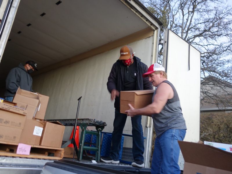 Food distribution specialist Ronald Buckman hands off last box to tribal staff as distribution specialist Naz looks on.