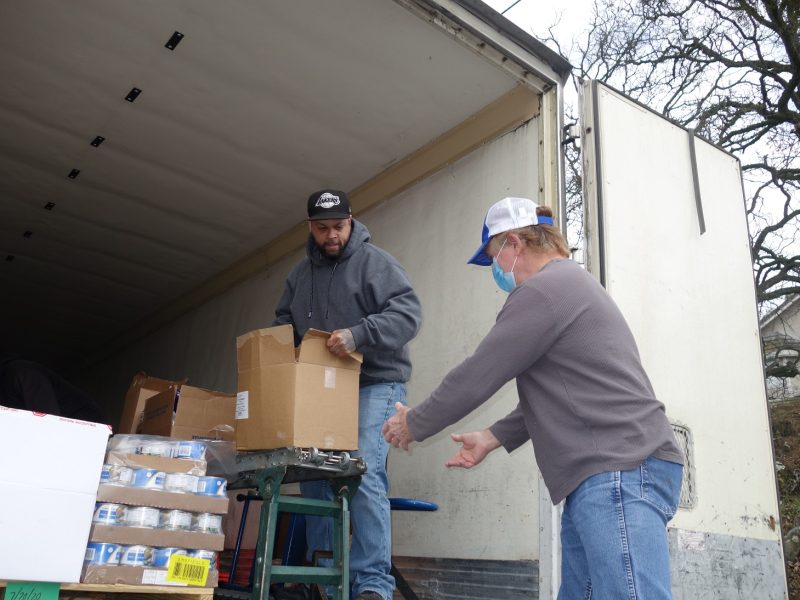 Specialist Ronald Buckman sorting distributions in background as Specialist Naz unloads conveyor.