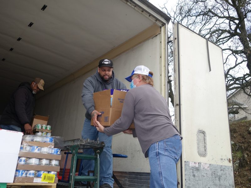 Specialist Ronald Buckman keeps conveyor loaded as Specialist Naz hands a box to tribal personnel.