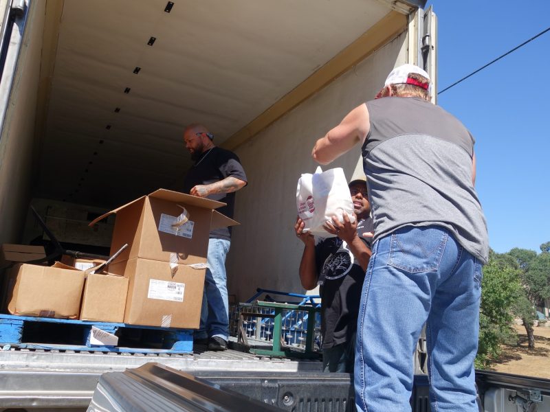 As Specialist Naz gathers more product, Specialist Ronald Buckman hands tribal staff part of one family's distribution. California Indian tribe unloading good supplies