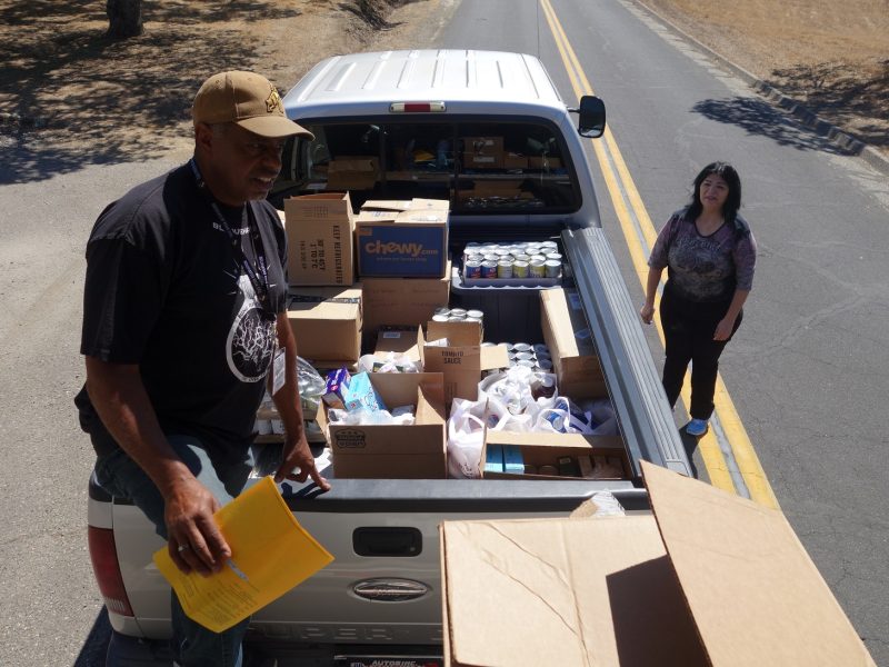 Chairperson Silvia Burley looks on as Specialist Ronald Buckman holds sign in sheet of newly enrolled recipient. California Valley Miwok Tribal staff helps unloading good supplies.