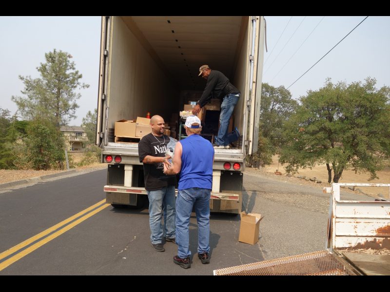 Specialist Naz and tribal staff exchange distribution product during discussion while specialist Ronald Buckman readies next distribution. Naz helps Tiger Paulk unloading good supplies for the California Valley Miwok Tribe.