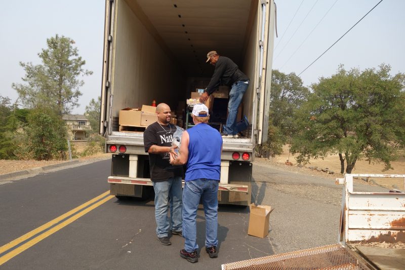 Specialist Naz and tribal staff exchange distribution product during discussion while specialist Ronald Buckman readies next distribution. Naz helps Tiger Paulk unloading good supplies for the California Valley Miwok Tribe.