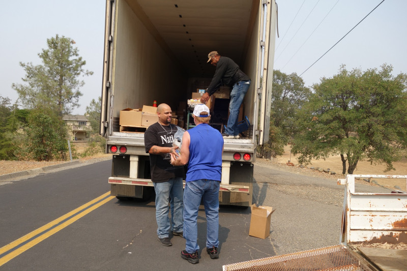 Specialist Naz and tribal staff exchange distribution product during discussion while specialist Ronald Buckman readies next distribution. Naz helps Tiger Paulk unloading good supplies for the California Valley Miwok Tribe.