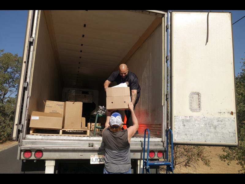Tule River Distribution Specialist Naz hands one of a family's many boxes of their distribution to tribal staff. California Valley Miwok Tribe's staff delivering good supplies.