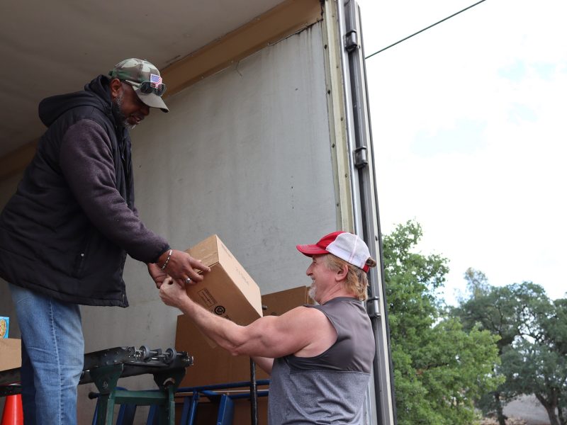 Specialist, Ronald Buckman while handing box to tribal staff gets a laugh
telling a joke from his old stand up routine, "Officer Gitmo". California Valley Miwok Tribe's staff Tiger Paulk taking good boxes from Ronald Buckman during a food distribution.