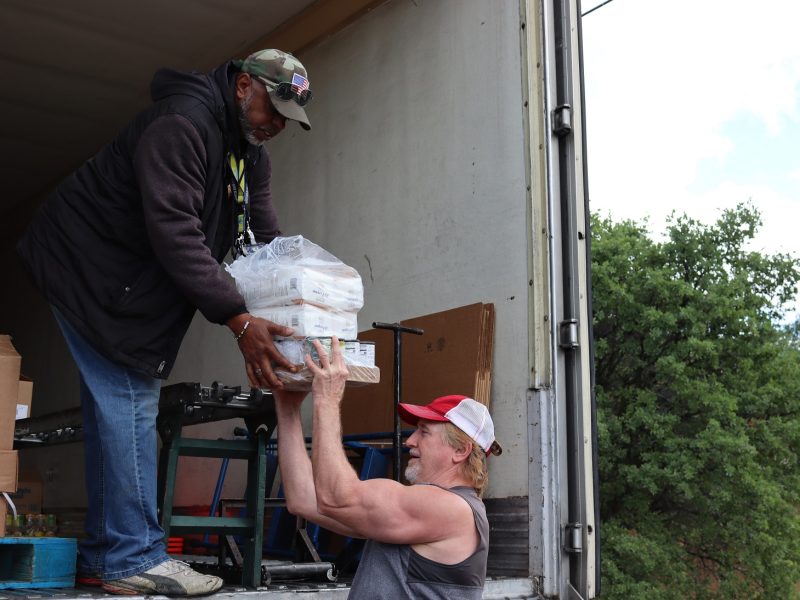 Ronald Buckman handing tribal staff member Tiger Paulk goods for the California Valley Miwok Tribe.