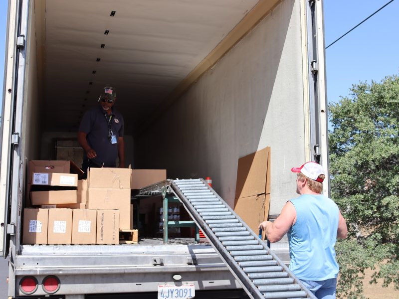 At the start of the distribution, Specialist Ronald Buckman seen looking over extra supplies needed to fulfill this month's distributions to additional recipients. Tiger Paulk and Ronald Buckman during a food distribution for the California Valley Miwok Tribe.