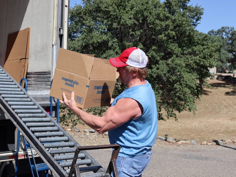 Tribal staff pulling just one of the many boxes that would be coming down the conveyor on this day. California Valley Miwok Tribe's staff Tiger Paulk carrying goods boxes during a distribution.