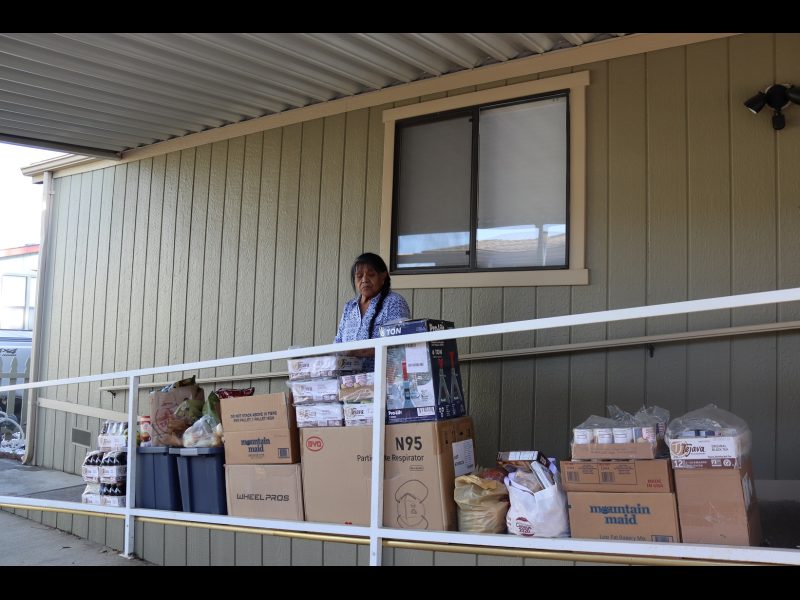 This view shows Program Director Mildred Burley with the May 2022 Food For Tribal Families delivery. California Indian tribe elder Mildred Burley standing in front of food supplies for the California Valley Miwok Tribe.