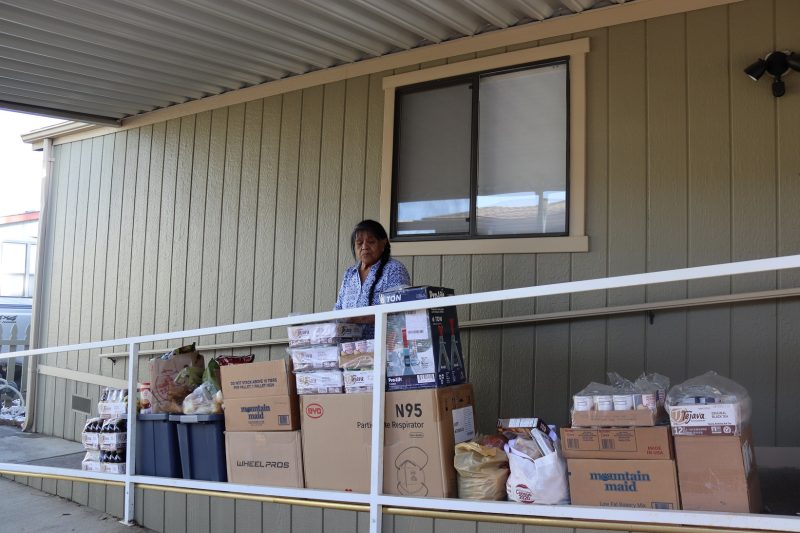 This view shows Program Director Mildred Burley with the May 2022 Food For Tribal Families delivery. California Indian tribe elder Mildred Burley standing in front of food supplies for the California Valley Miwok Tribe.