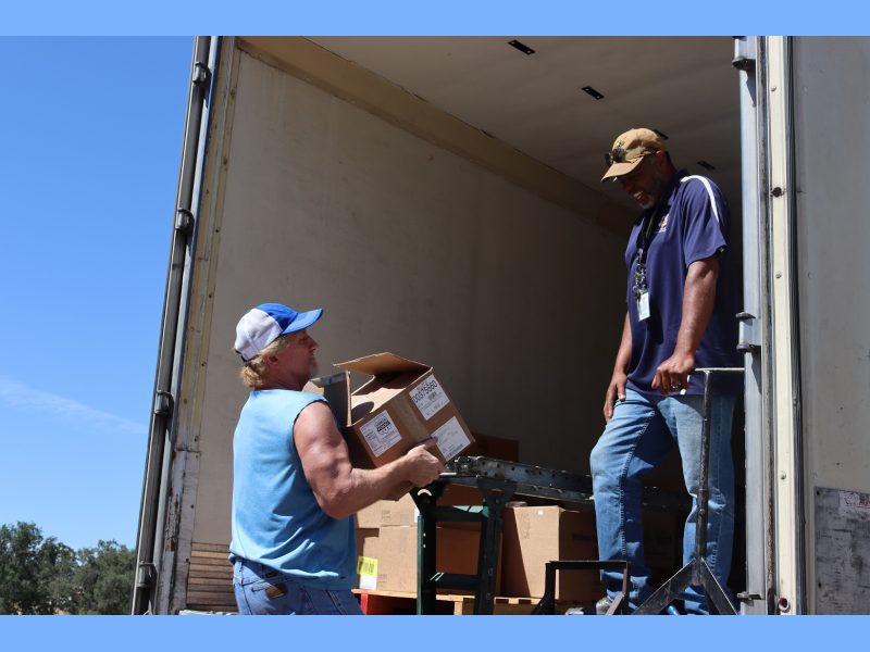 Specialist, "Ronald Buckman" having a good time with staff as the last of another distribution gets loaded. Ronald Buckman and Tiger Paulk loading food supplies into a truck.