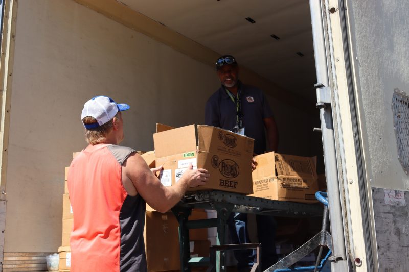 Tribal staff working with Specialist Ronald Buckman exchange information while fulfilling recipients distributions. California Valley Miwok Tribe staff member Tiger Paulk is helping Ronald Buckman to unload good supplies.