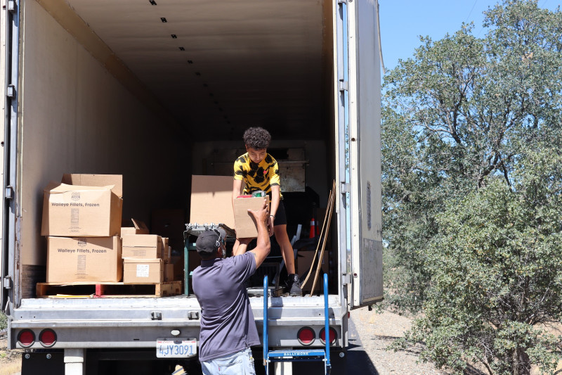 Here another picture shows DuRon working the conveyor and working with
his father making sure all distributions are unloaded. Ronald Buckman and Duron Buckman unloading good supplies for the California Valley Miwok Tribe