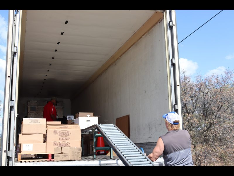Tribal Staffer looks on as Specialist Ronald Buckman prepares one of the events distributions. California Valley Miwok Tribe staff Tiger Paulk helps unloading goods.