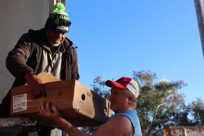 Ronald Buckman handing food down to tribal staff. Ronald helping Tiger unloading the good supplies for the California Valley Miwok Tribe.