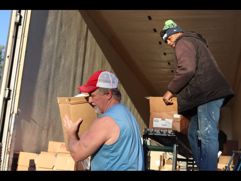 Ronald Buckman looks on with more distribution as tribal staffer carries
a previous item. Ronald Buckman and Tiger Paulk carrying goods supplies.