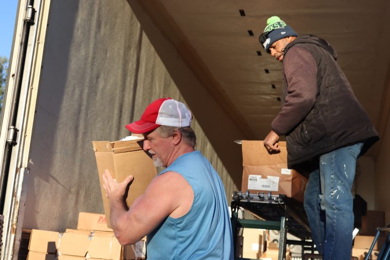 Ronald Buckman looks on with more distribution as tribal staffer carries
a previous item. Ronald Buckman and Tiger Paulk carrying goods supplies.