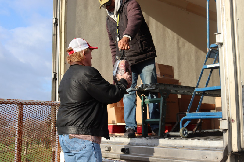 During food drive, this picture was taken showing the addition of the holiday hams given to each recipient. Ronald Buckman giving holiday ham to Tiger Paulk, CVMT tribal staff.