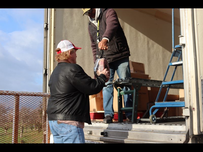 During food drive, this picture was taken showing the addition of the holiday hams given to each recipient. Ronald Buckman giving holiday ham to Tiger Paulk, CVMT tribal staff.