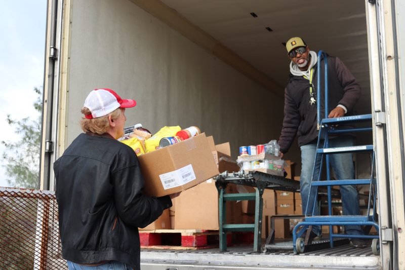 One of the day's many distributions. Tule River Food Distribution Department, Ronald Buckman and tribal staff. Tule River Food Distribution Department Ronald Buckman helping CVMT tribal staff Tiger Paulk.