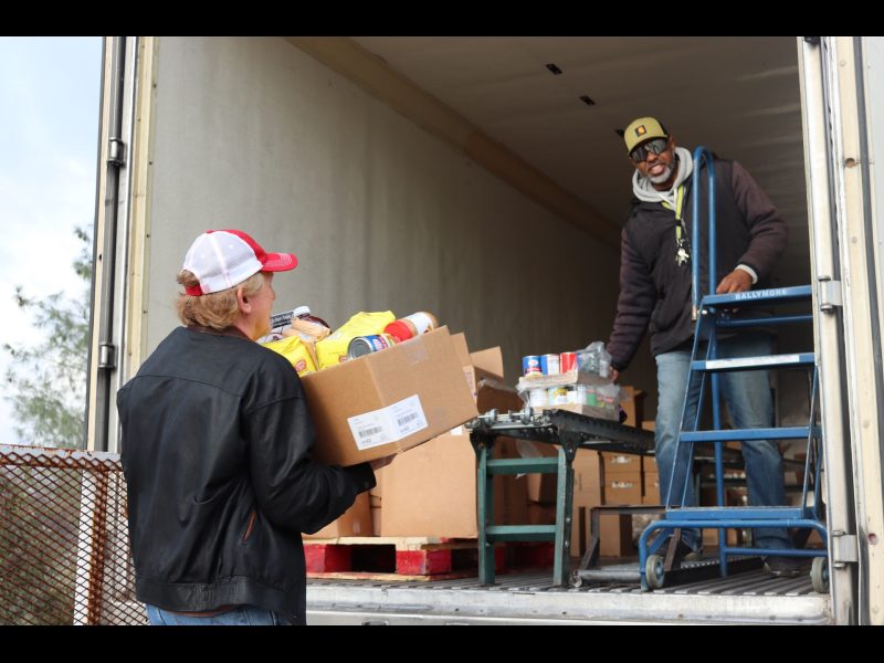 One of the day's many distributions. Tule River Food Distribution Department, Ronald Buckman and tribal staff. Tule River Food Distribution Department Ronald Buckman helping CVMT tribal staff Tiger Paulk.
