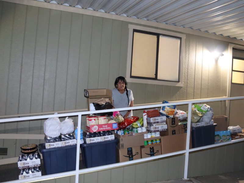 Food For Tribal Families Program Director Mildred Burley stands amid a vast array of what was delivered. Tribal elder Mildred Burley standing in front of goods being delivered to the Miwok tribe.