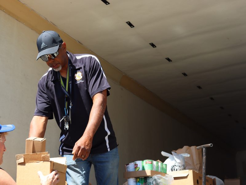 Tule River USDA Food Distribution Specialist Ronald Buckman hands the first package of one family's allotment to California Valley Miwok tribal staffer Tiger Paulk.