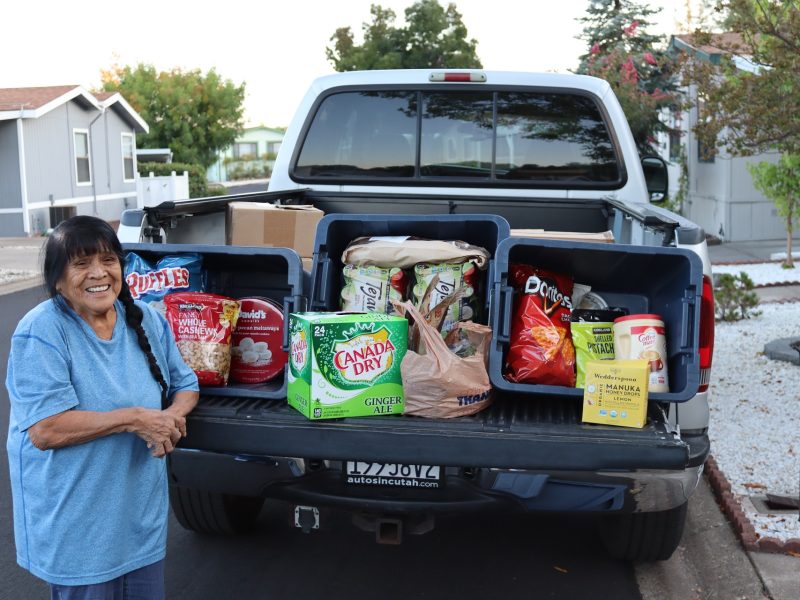 Tribal elder Mildred Burley with goods being delivered to Miwok tribe members.