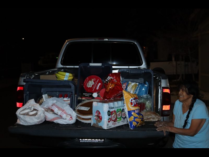An array of frozen meats, pies, festive snacks, fruits,
creamers, sodas, vegetables and breads and of course a very jubilant Food For Tribal Families Program Director. California Valley Miwok Tribal elder Mildred posing in front of foods to be delivered to Native families.
